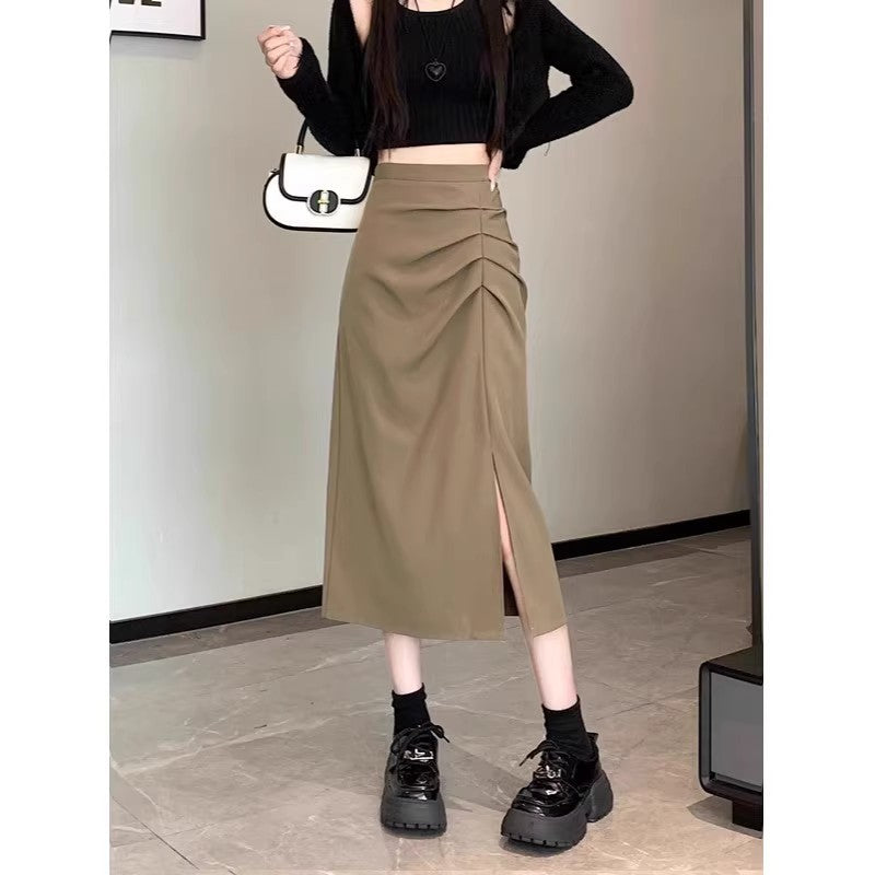 Person wearing a black crop top, beige skirt, and black shoes in an indoor setting.