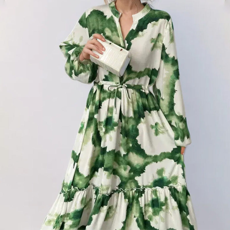Green and white floral dress worn by a person on a plain background