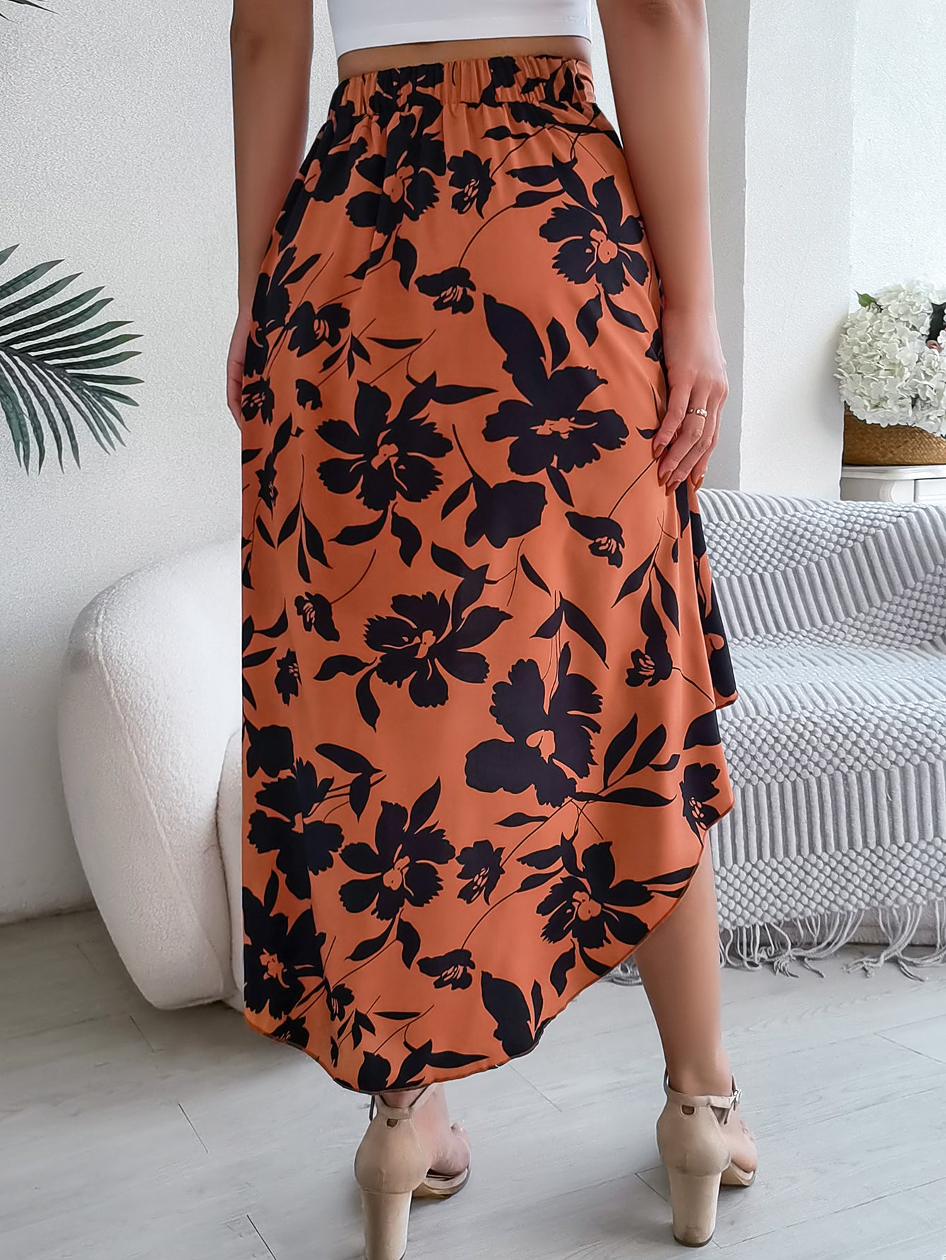 Person wearing an orange floral skirt in a room with a white couch and decorative items.