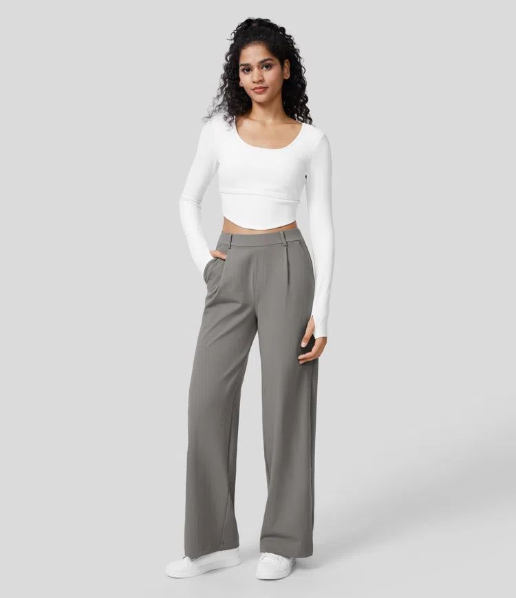 Woman wearing a white long-sleeve top and gray high-waisted pants on a light gray background