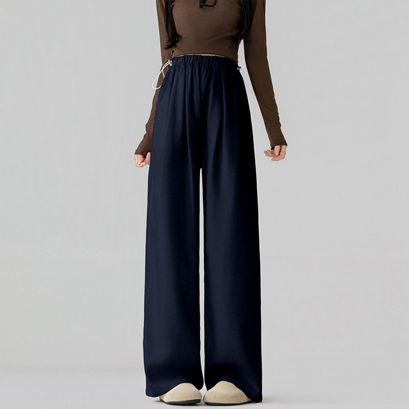 Person wearing a brown long-sleeve top and navy wide-leg pants on a gray background