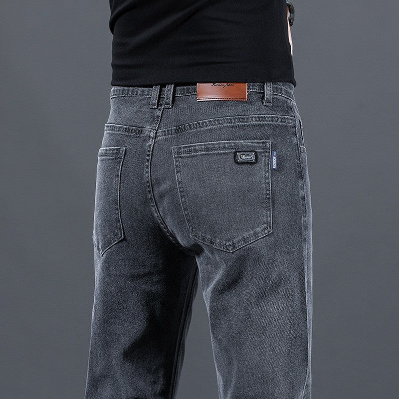 Person wearing gray jeans with a visible brand logo on a gray background