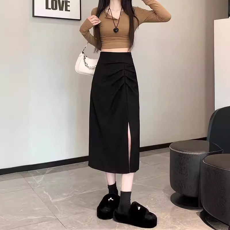 Woman wearing a brown long-sleeve top and black skirt in an indoor setting.