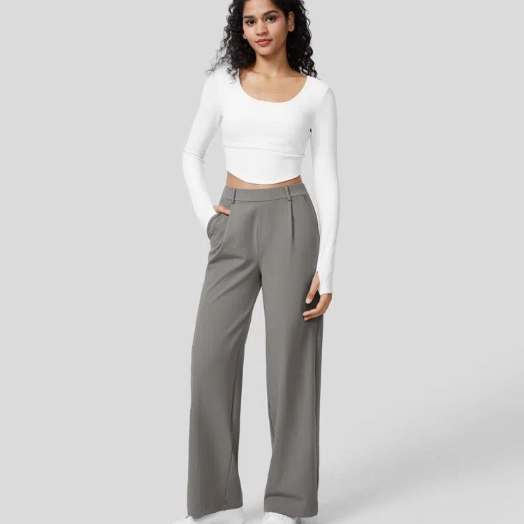 Woman wearing a white long-sleeve top and gray high-waisted pants on a light gray background