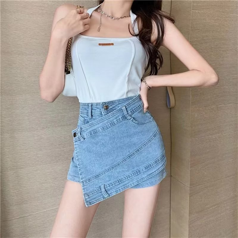 Woman wearing a light blue denim skirt and white top against a beige wall.