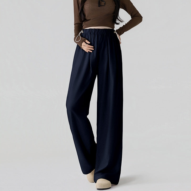Person wearing a brown top and navy wide-leg pants on a light gray background