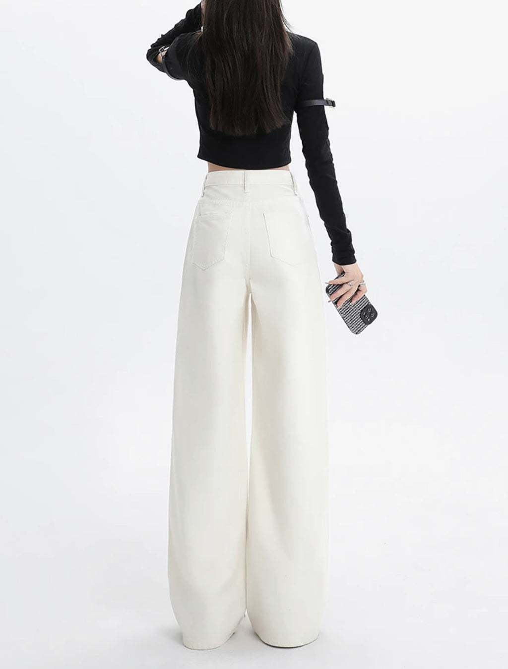 Person wearing white wide-leg pants and a black long-sleeve top on a white background