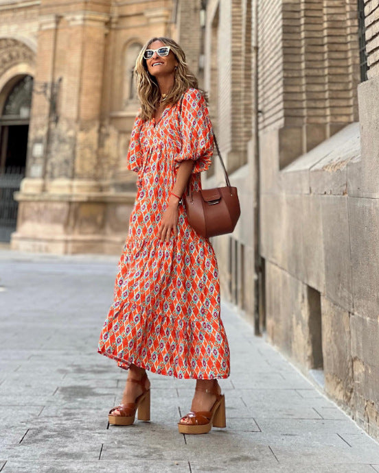 Woman in a patterned dress standing on a street with a building in the background