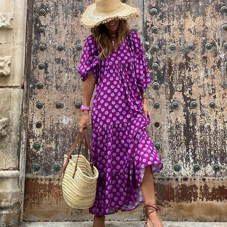 Woman in a purple dress with white polka dots standing in front of an old door.