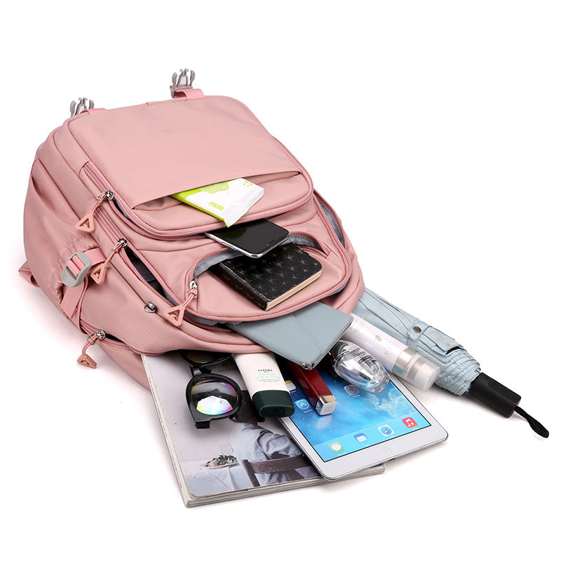 Pink backpack with various items including a phone, umbrella, and books