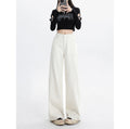 Person wearing a black cropped top and white wide-leg pants on a white background