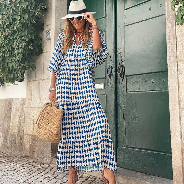 Woman in a blue and white patterned dress standing in front of a green door.